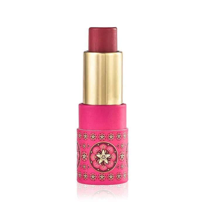Vibrant pink lipstick with gold accents and intricate floral design on the tube.