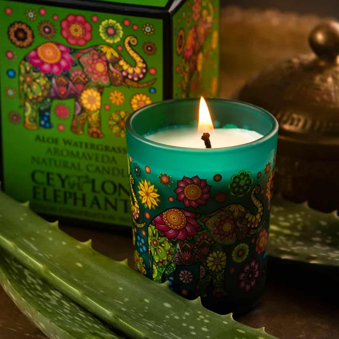 Yellow, pink, green floral candle from Spa Ceylon with decorative elephant design.